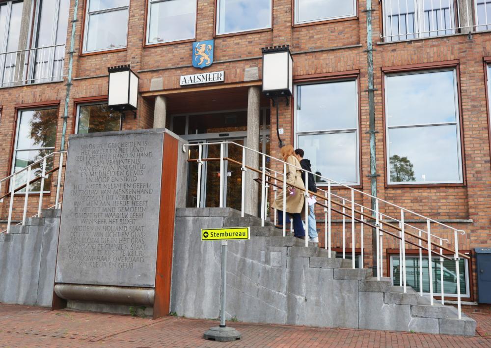 Twee mensen lopen het raadhuis van Aalsmeer binnen om te gaan stemmen