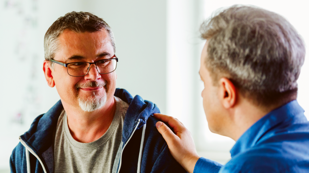 Man geeft andere man bemoedigend een schouderklopje
