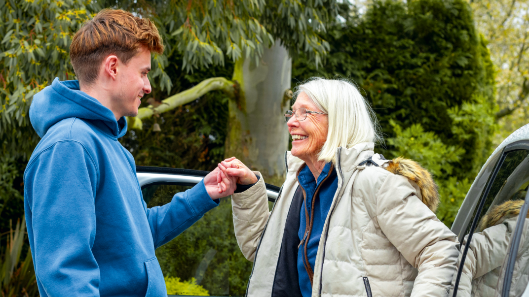 Dame stapt uit de auto met hulp van tienerjongen