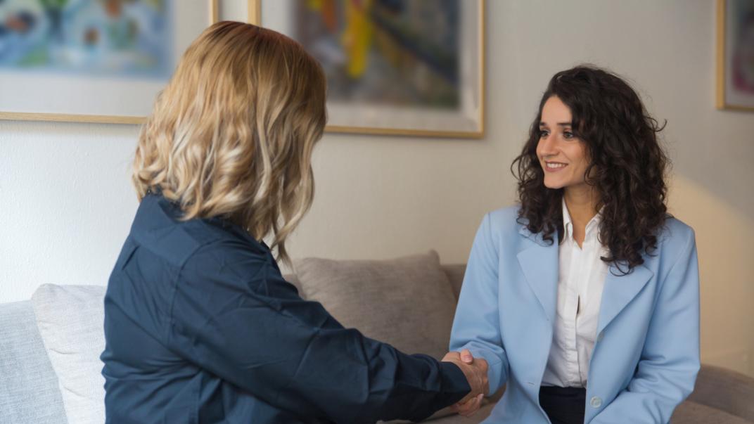 Twee dames op een bank schudden elkaar de hand